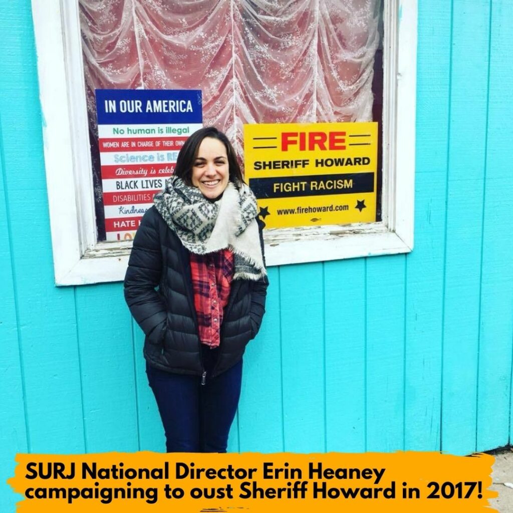 image shows a white woman in front of a bright teal building. She is bundled in a puffy coat and has a scarf on. The caption reads "SURJ National Director Erin Heaney campaigning to oust Sheriff Howard in 2017!"