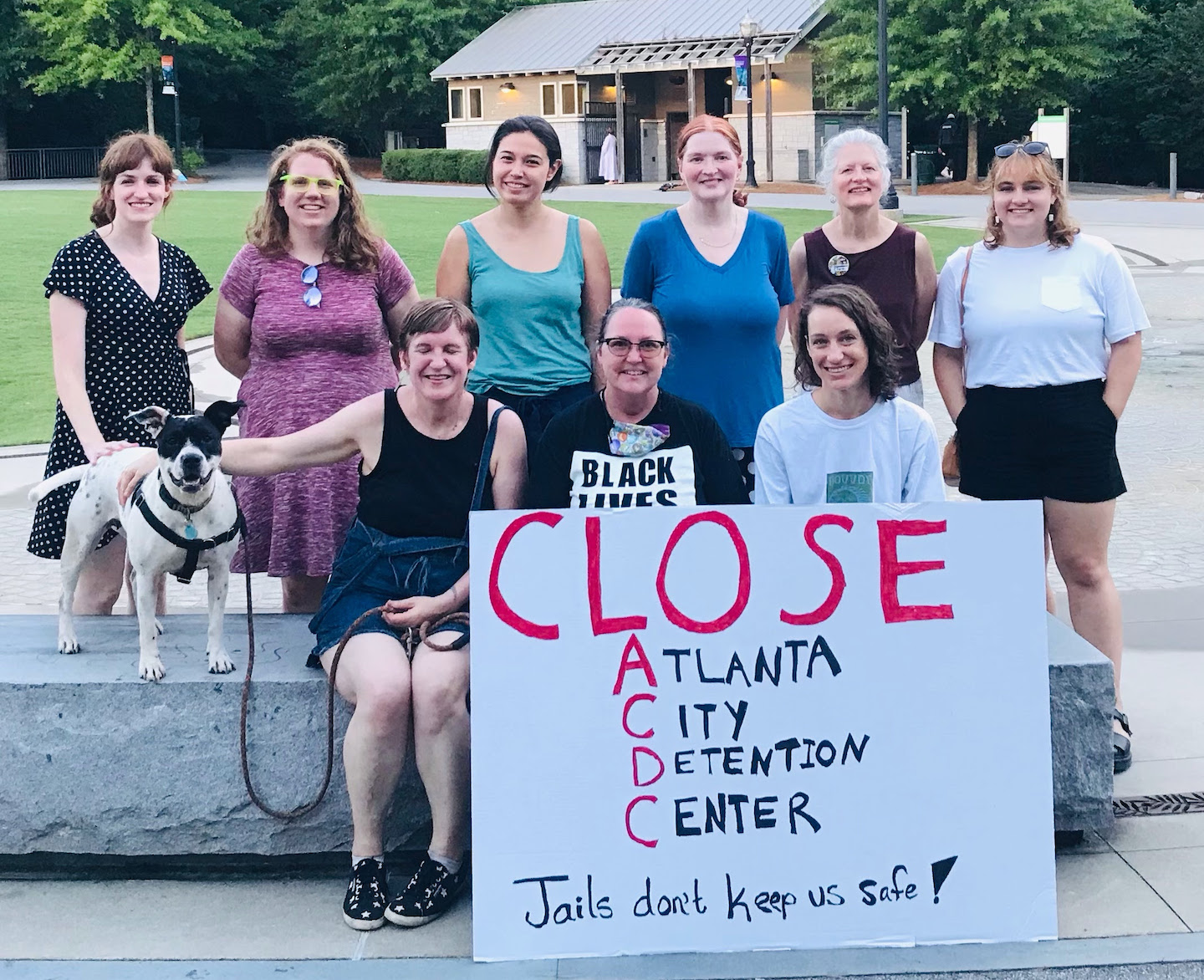 image shows two rows of white activists (9 total) posing next to a sign that reads "close atlanta city detention center. Jails don't keep us safe!"