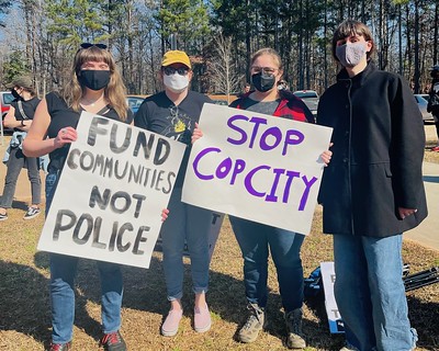 Protestors with sign 'Stop Cop City' and 'Fund Communities Not Police'