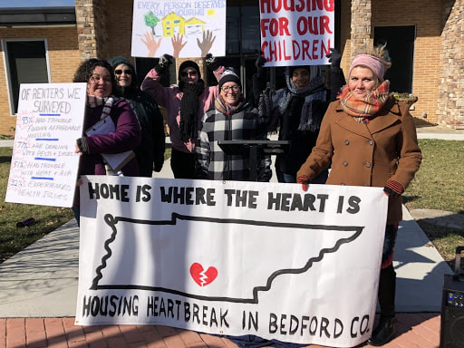 Members of BCLP stand with home is where the heart is sign