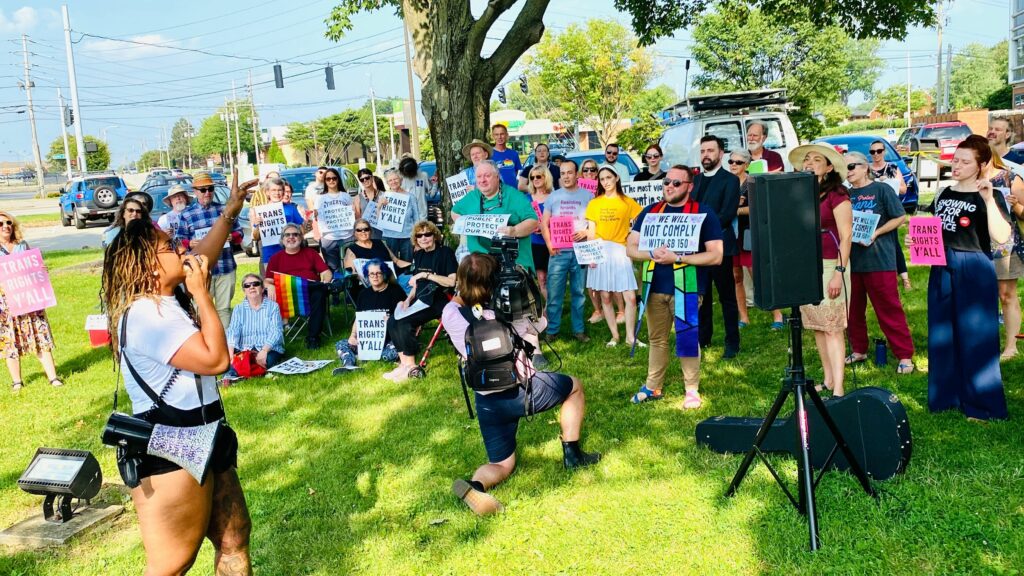 Image of a group of people listening to a speaker on bright green grass in Louisville KY