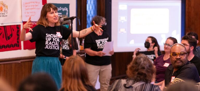 SURJ member speaking at a mic in front of an audience.